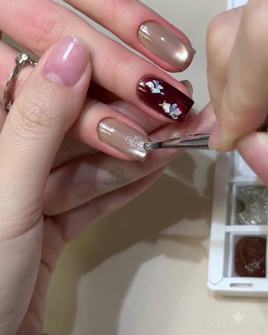 Un pennello fine che tampona materiali glitterati riflettenti e lucidi su ununghia in gel cat-eye neutra.