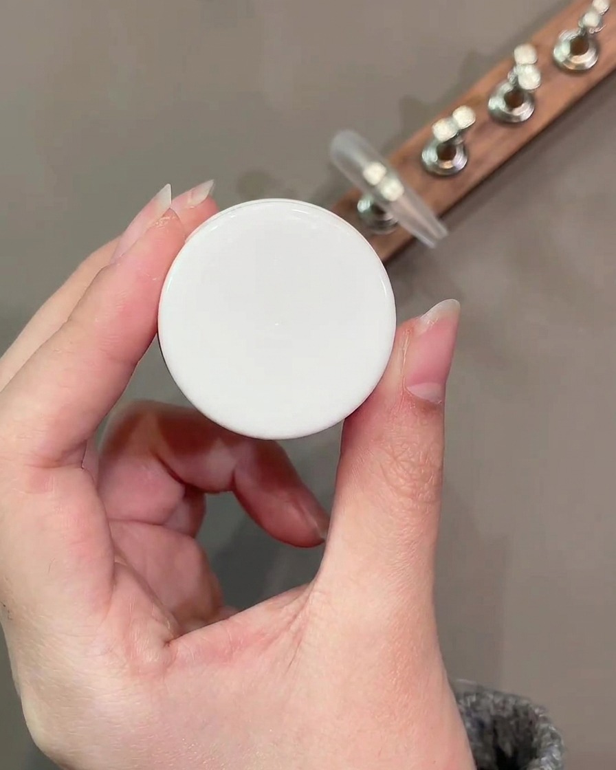 Un pennello da gel piatto applica uno strato uniforme di colore base nude numero 34 sulla superficie dellunghia.