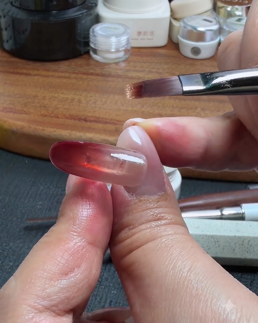 Un pennello per unghie che raccoglie una piccola quantità di gel base da trascinare verso lalto dal blocco rosso, creando un effetto sfumato ombre.