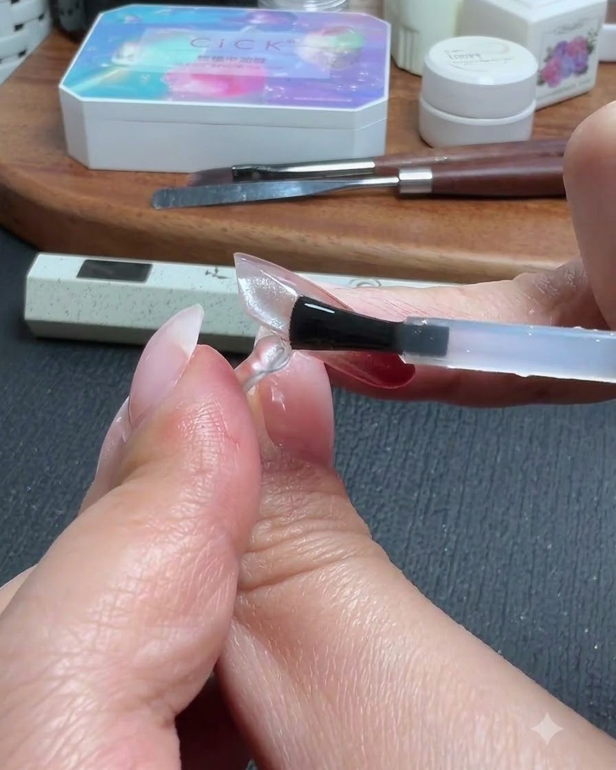 Un pennello che applica uno strato di top coat su unestensione per unghie trasparente e traslucida.