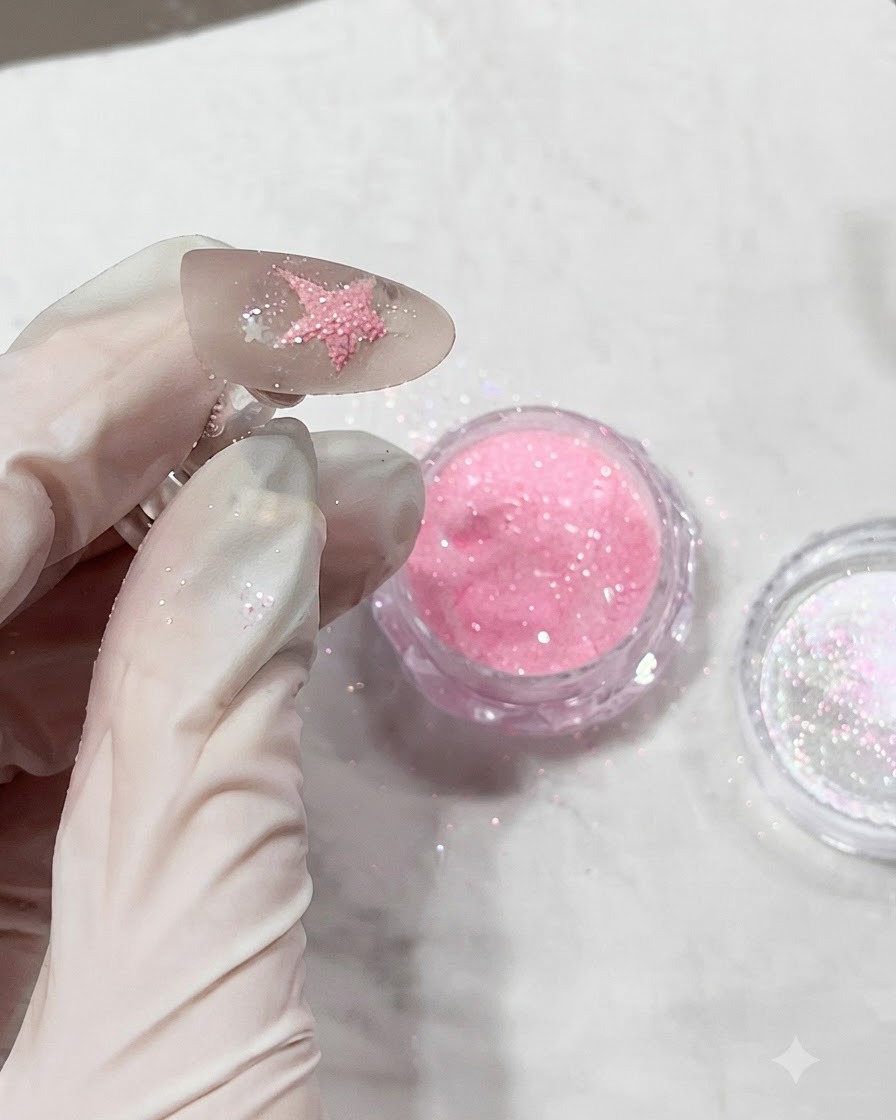 Ununghia ricoperta di polvere di diamante rosa texturizzata appena prima di essere polimerizzata sotto una lampada.