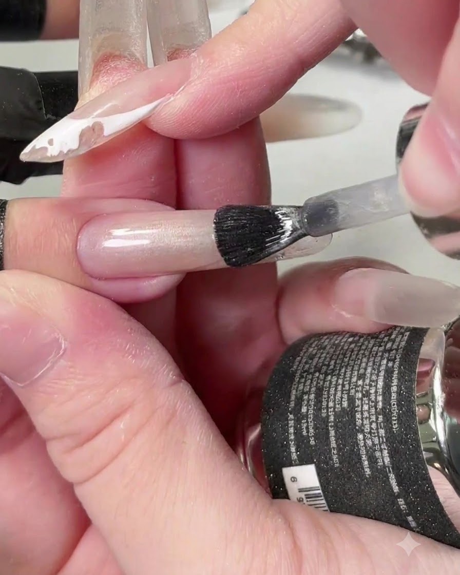 Un pennello che applica il gel crystal cat-eye trasparente lungo tutta la lunghezza dellunghia.