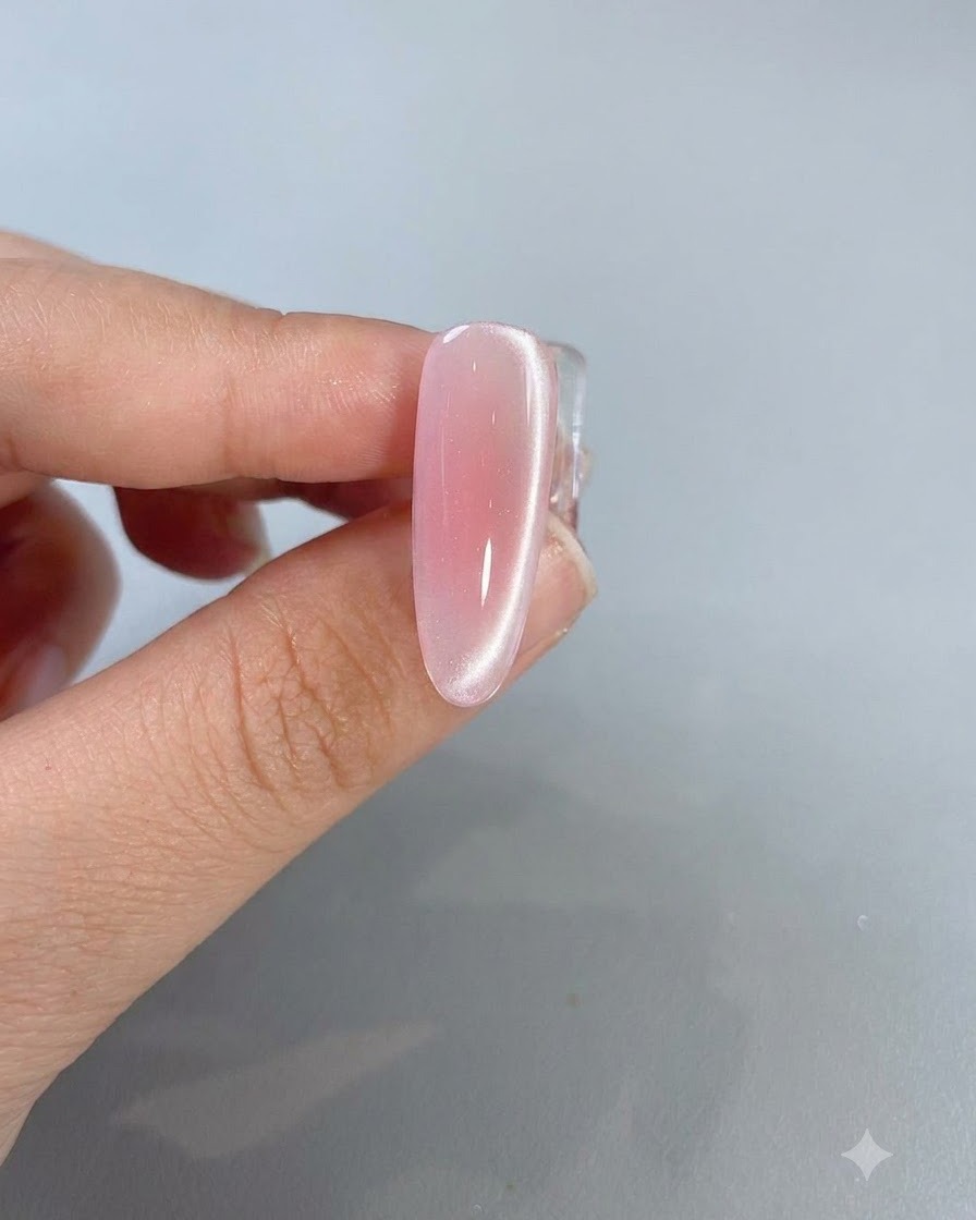 Un primo piano di ununghia rosa cat-eye completata che mostra una brillante linea di riflessione della luce che corre lungo il lato.