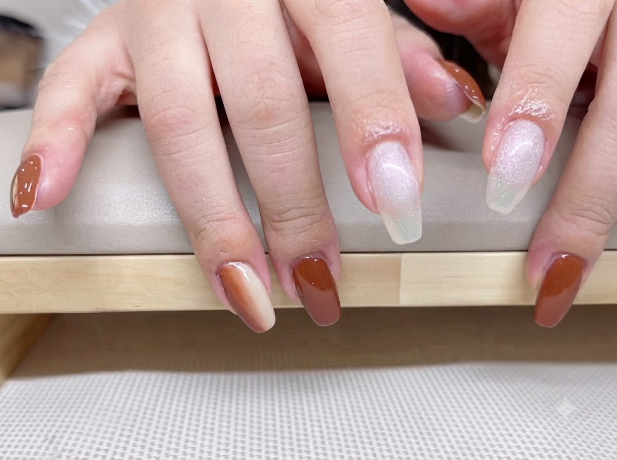 Primo piano di mani con base coat traslucida bianco latte applicata su dito indice e medio.