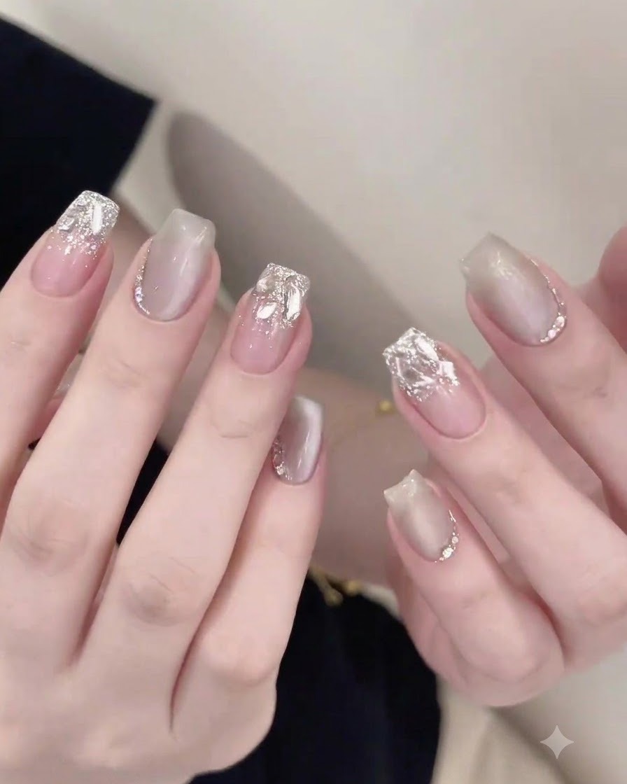 Un pennello da unghie che applica con cura un top coat lucido attorno ai rhinestones incorporati su ununghia finita.