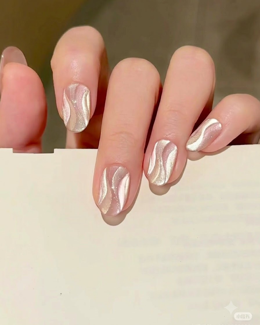 Un pennello liner fine che dipinge una seconda forma di nastro curvo usando il gel cat eye oro proprio accanto al nastro argento polimerizzato.