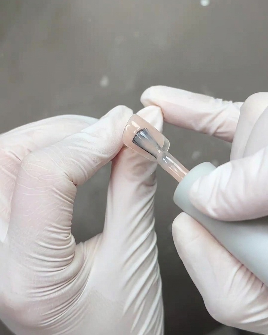 Un pennello che applica uno strato spesso di top coat trasparente e lucido sopra la nail art finita.
