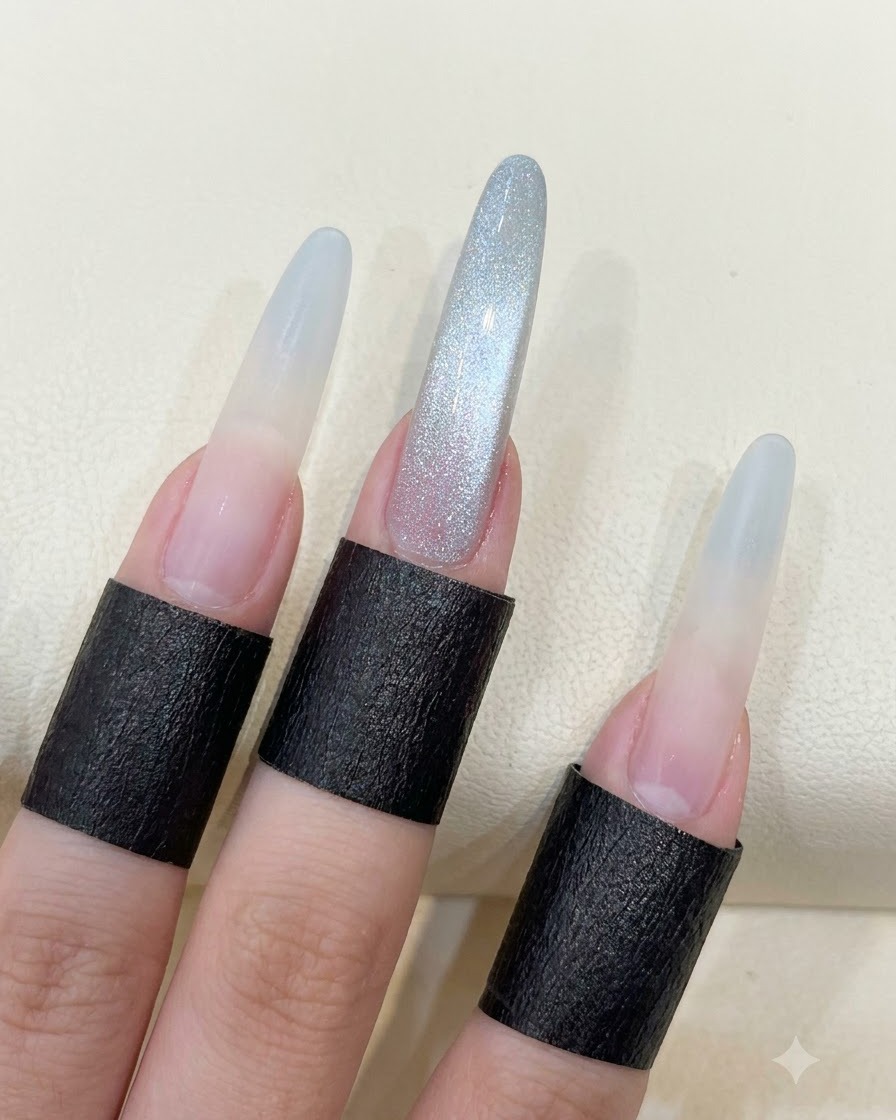 Una mano che mostra unghie lunghe a mandorla con il riflesso cat eye a perla di vetro completato.