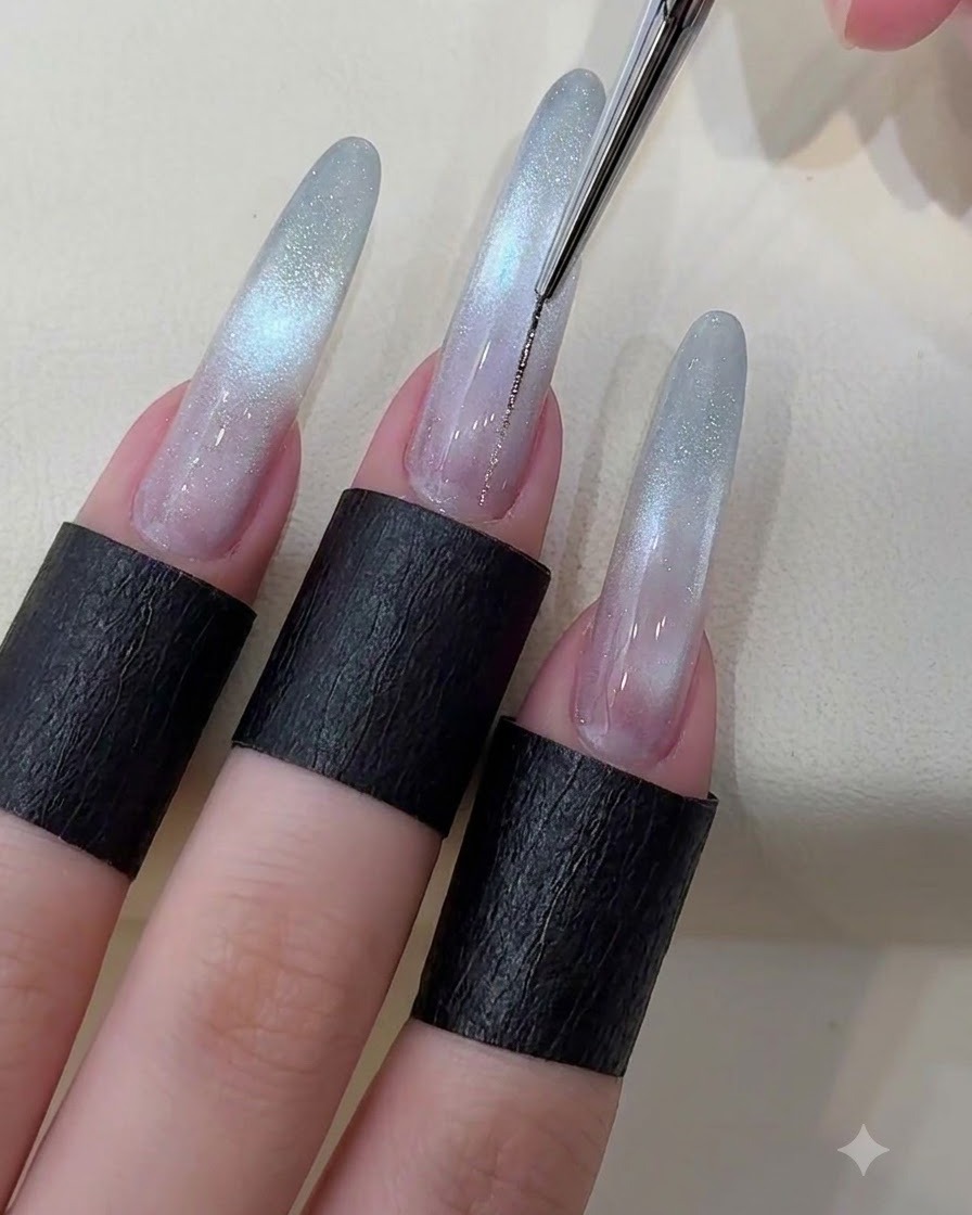 Un pennello liner sottile che disegna una sottile linea color argento metallizzato lungo il centro di ununghia cat eye stellata.