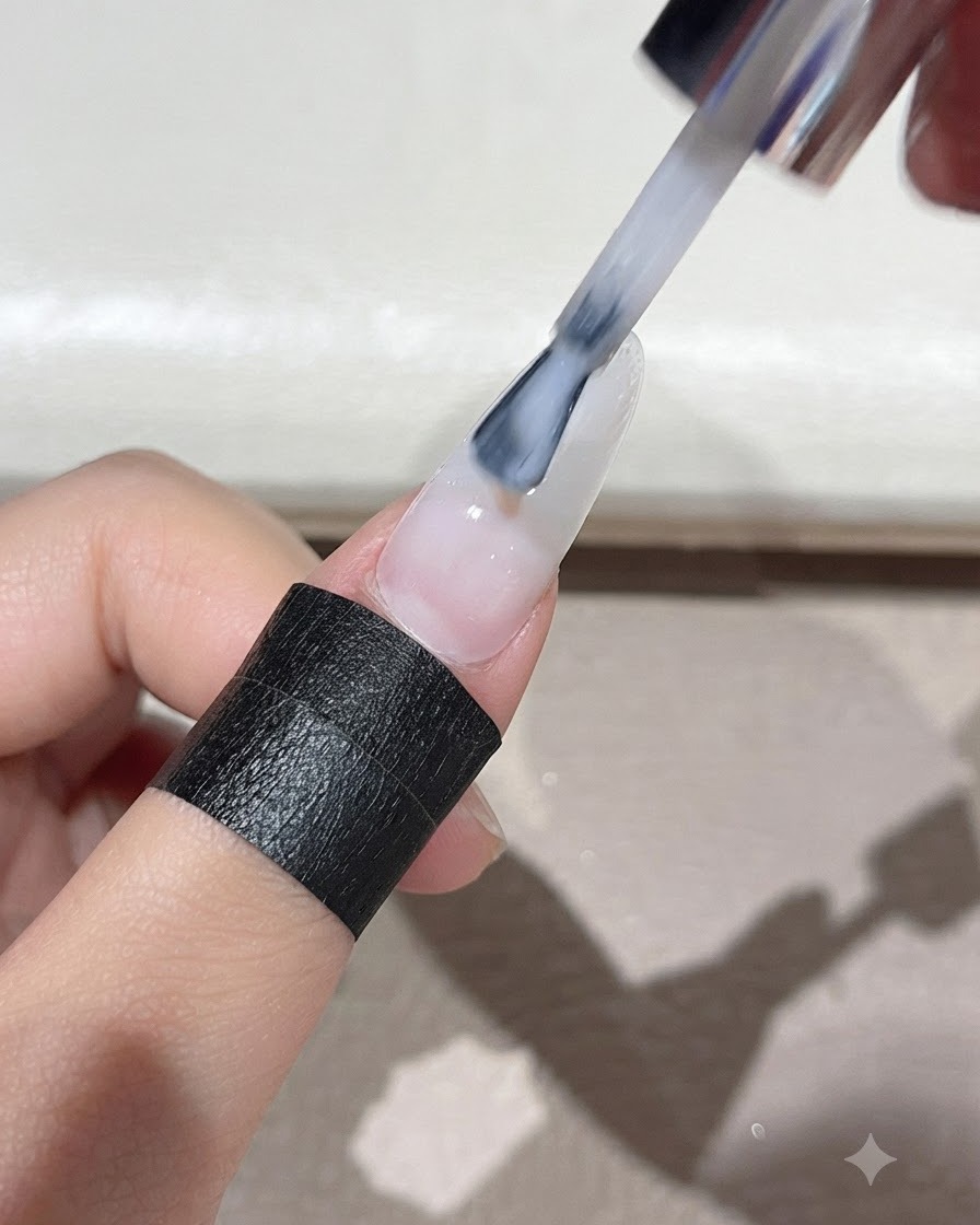 Un pennello che stende il gel autolivellante bianco latte in modo uniforme su tutta la superficie dellunghia.