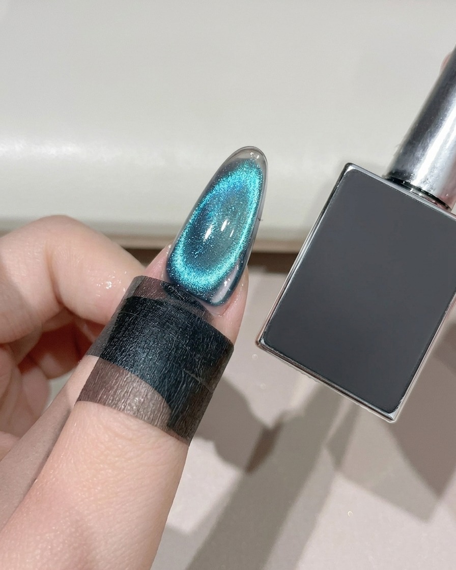 Ununghia cat-eye finita che viene polimerizzata sotto una lampada di polimerizzazione UV/LED accanto a un flacone di gel scuro.