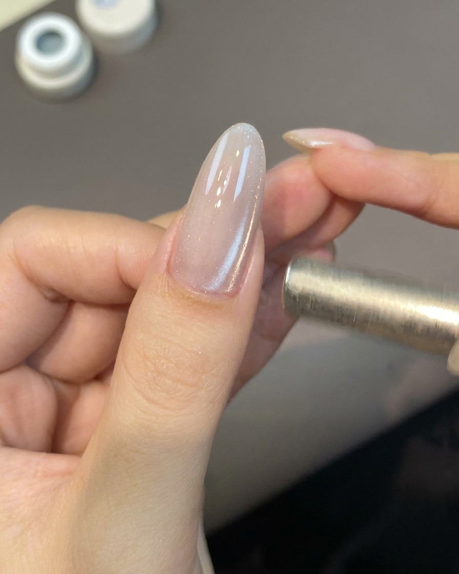 Un piccolo strumento magnetico a bacchetta si libra vicino a ununghia per attivare le particelle di gel cat-eye.