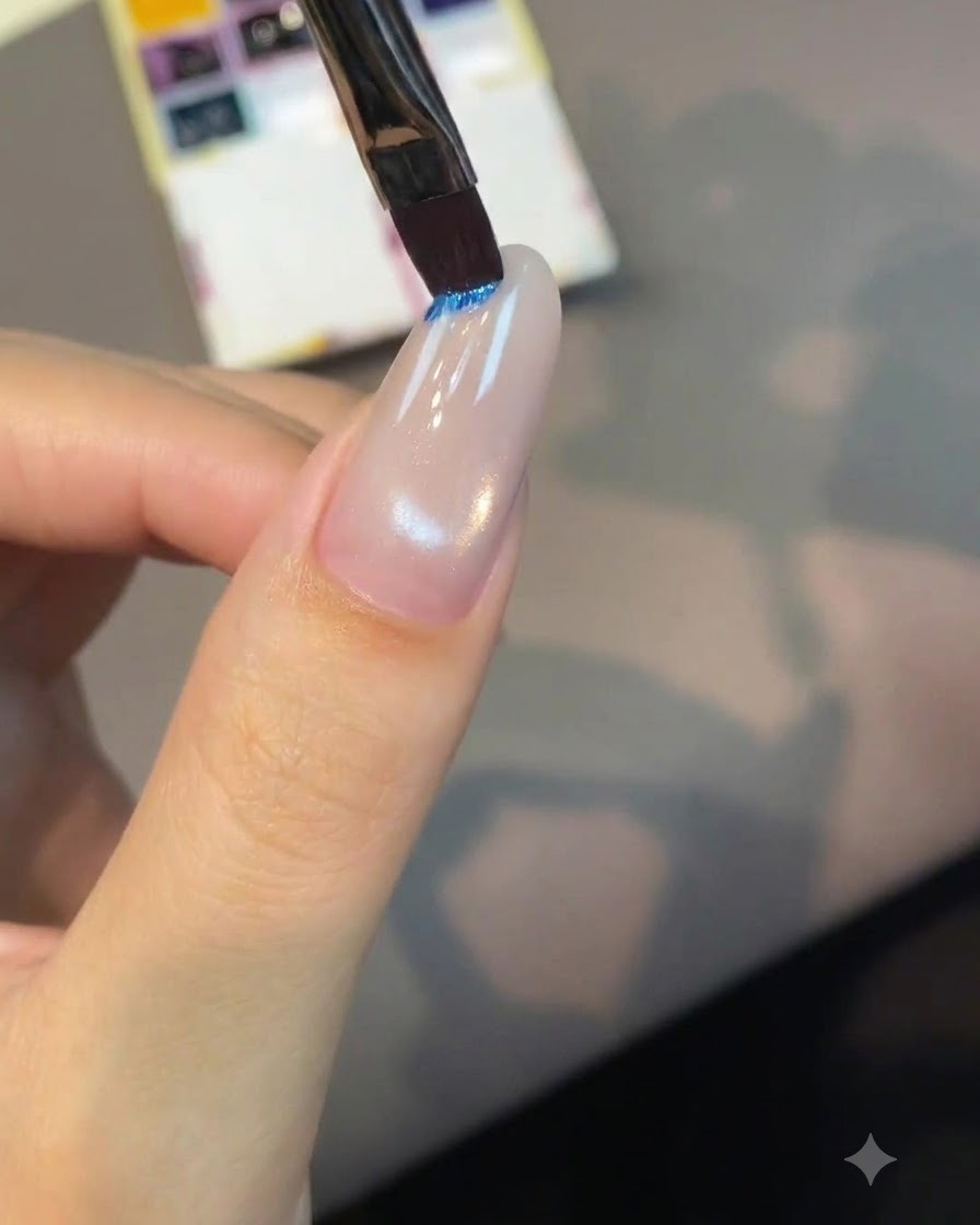 Un pennello piatto per nail art si intinge in una tavolozza di pigmento blu brillante.