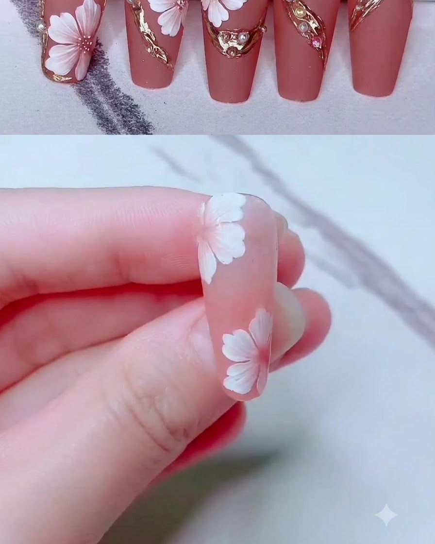 Un pennello liner sottile che disegna delicate linee in gel dorato attorno a un design di nail art floreale.