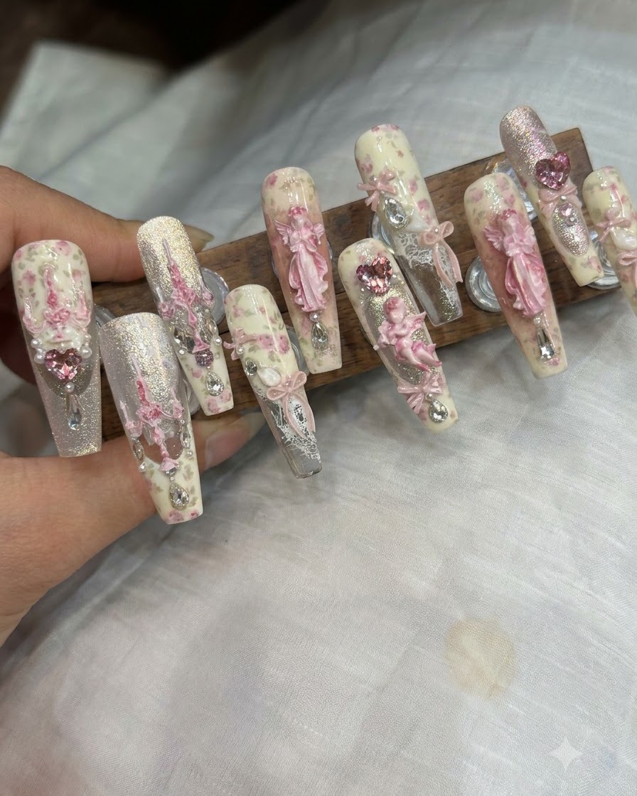 Un paio di pinzette posiziona un fiocco 3D e degli strass su ununghia completata.