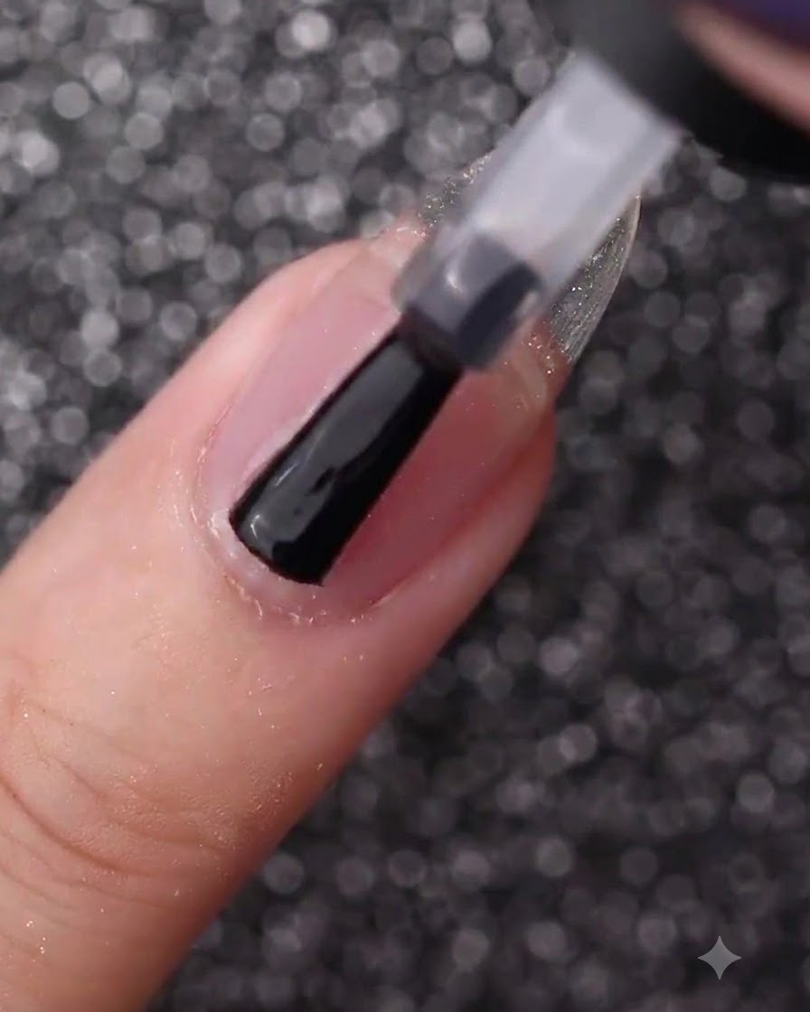 Una mano che utilizza un pennello da bottiglia per rivestire ununghia naturale nuda con gel base trasparente.