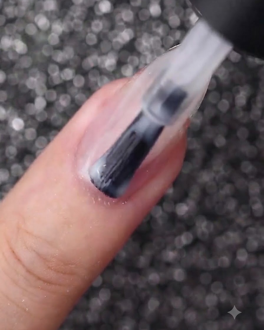 Un pennello da unghie che applica uno strato uniforme di smalto gel bianco latte su ununghia di forma ovale.