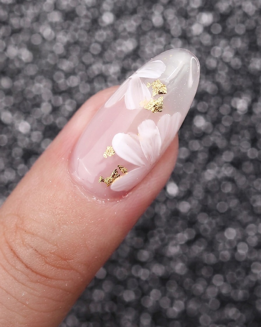 Un primo piano di petali di fiori bianchi dipinti che si sovrappongono luno sullaltro su uno sfondo di unghia in gel.