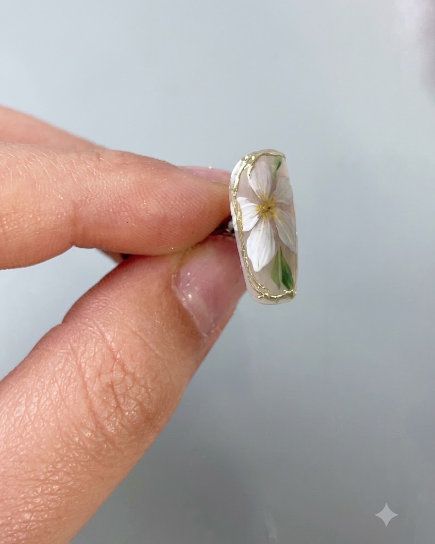 Un pennello fine per nail art che applica un top coat protettivo trasparente precisamente sopra un delicato bordo in cromo oro su ununghia con base nude.