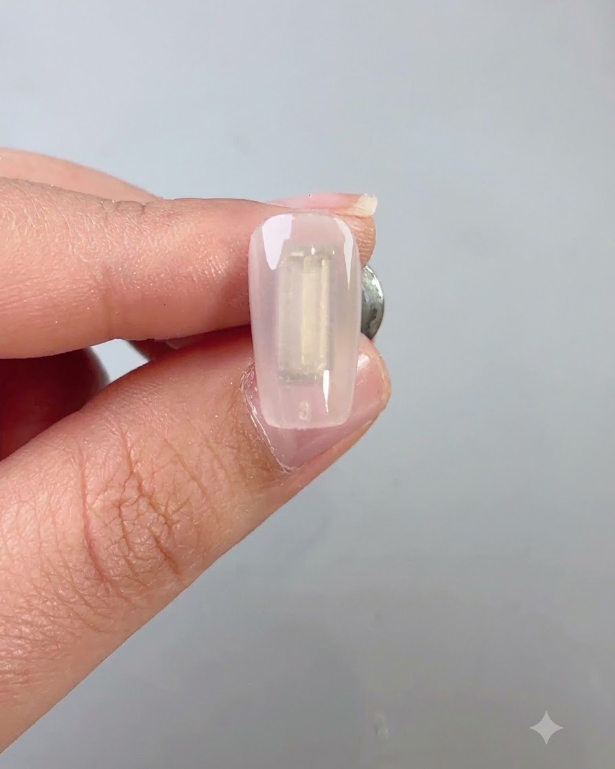 Un pennello per unghie che applica uniformemente una mano di gel cat eye wilderness verde scuro su ununghia.