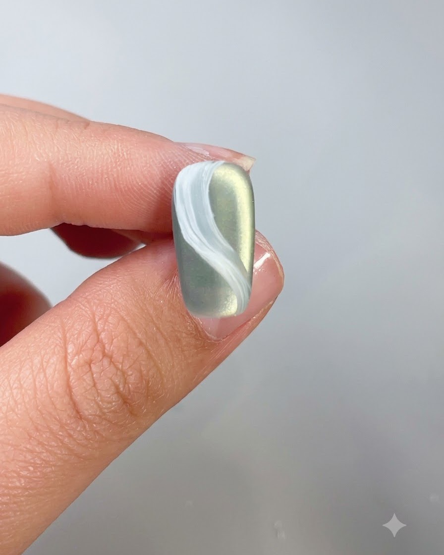 Un primo piano di ununghia con un design a nuvola bianca rivestita di top coat.