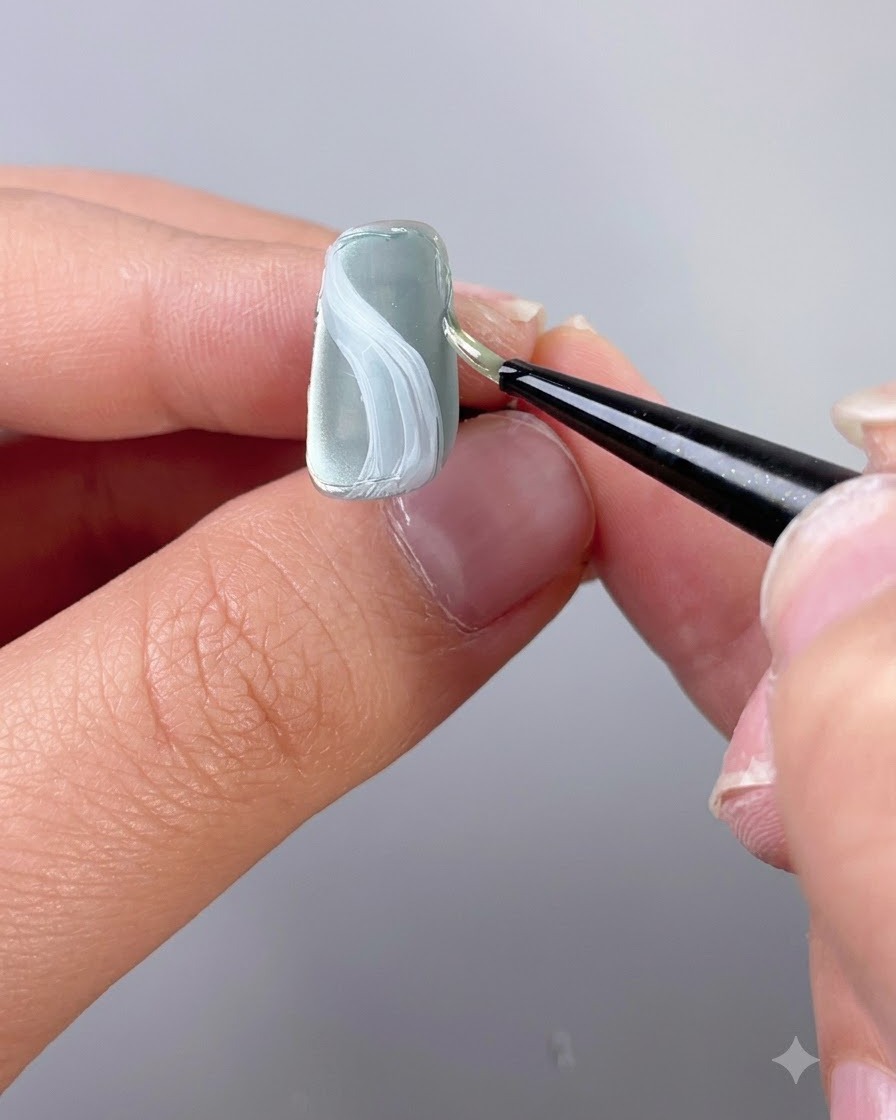 Un pennello per dettagli fini che applica il gel per scultura texturizzato lungo il bordo di ununghia.