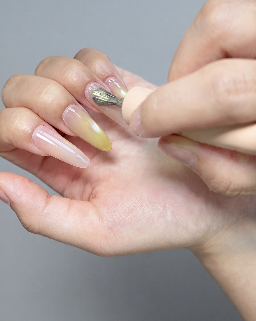Un forte magnete che sovrasta ununghia lucida in gel cat-eye per modellare le particelle magnetiche.