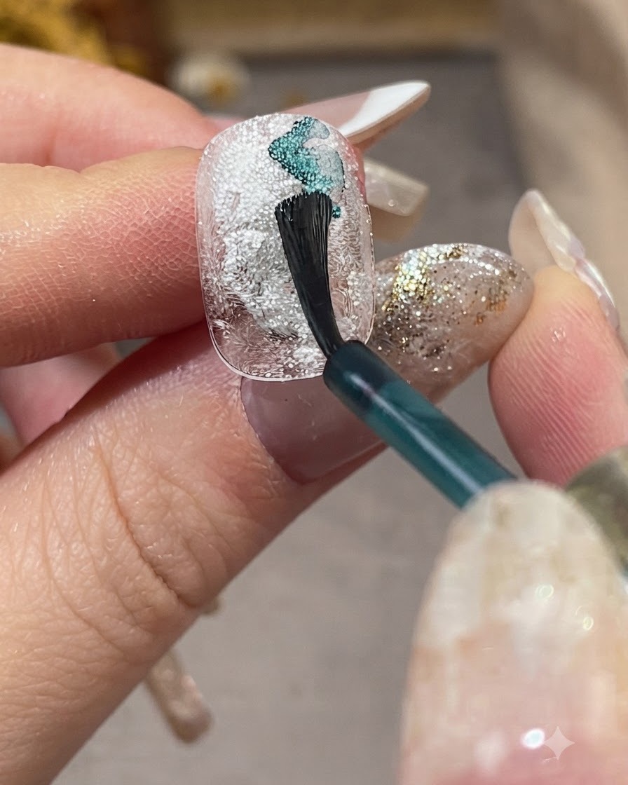 Un pennello da unghie applica il liquido sfumante azzurro in diagonale su ununghia bianca strutturata.