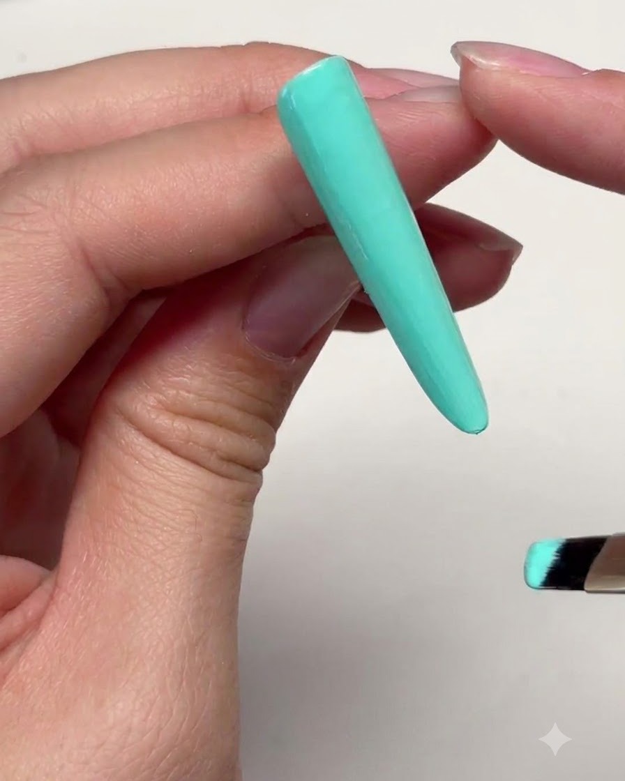 Una lunga unghia ricostruita verde menta con uno strato sottile di gel applicato vicino al giro cuticole.