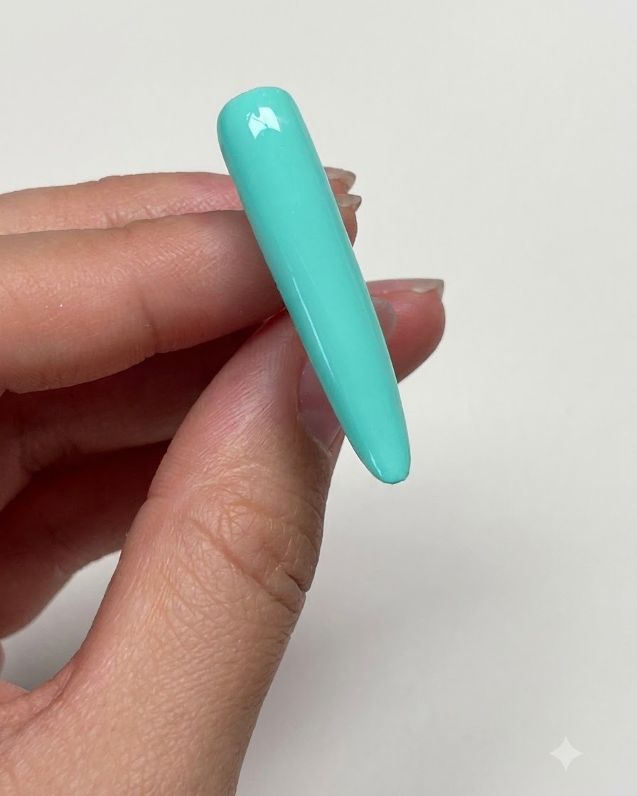 Una mano che pulisce la superficie dellunghia verde menta polimerizzata con un pad imbevuto di cleaner per rimuovere la dispersione.