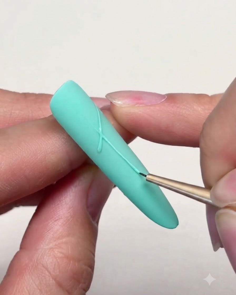 Un pennello liner sottile che disegna linee precise per connettere le punte di una stella su ununghia verde menta.