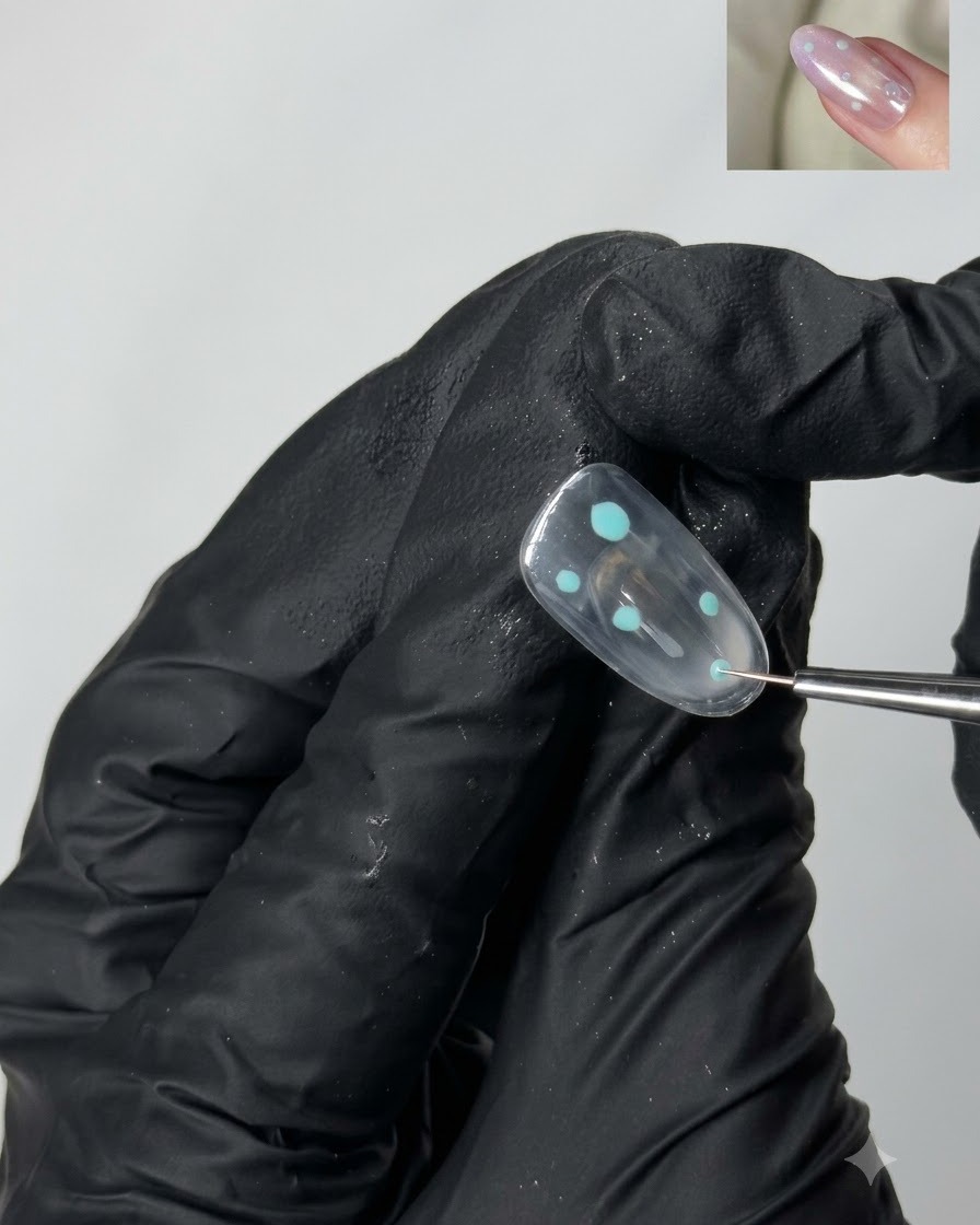 Un pennello da dettaglio fine che posiziona piccoli accenti a punto turchese su una superficie di unghia in gel trasparente.