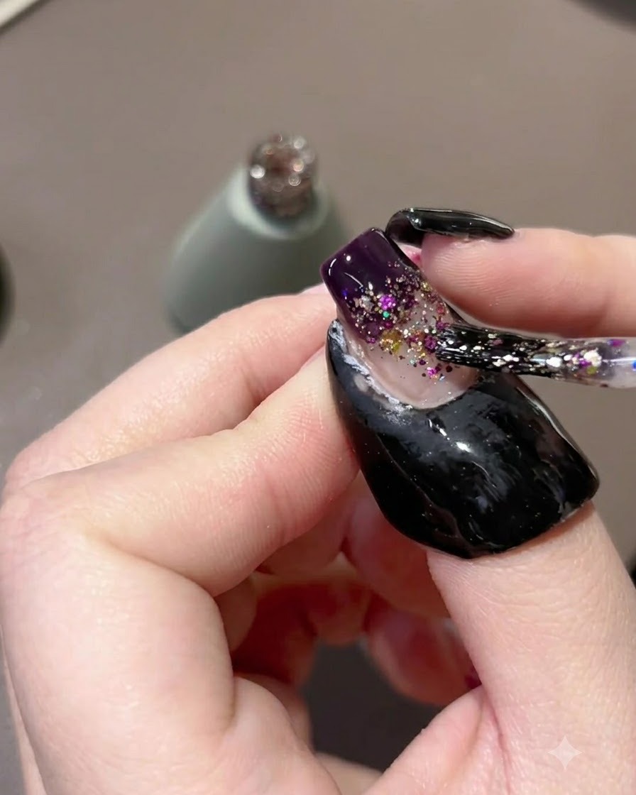 Un pennello per unghie tampona e trascina le particelle di glitter viola verso il basso per formare un gradiente.