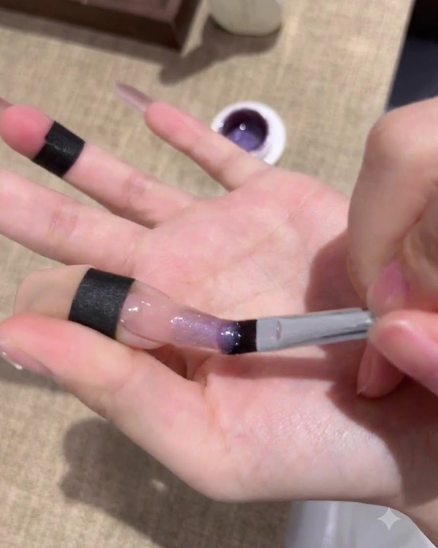 Unghie in fase di polimerizzazione sotto una lampada UV/LED dopo lapplicazione del primo strato di gel cat-eye viola.