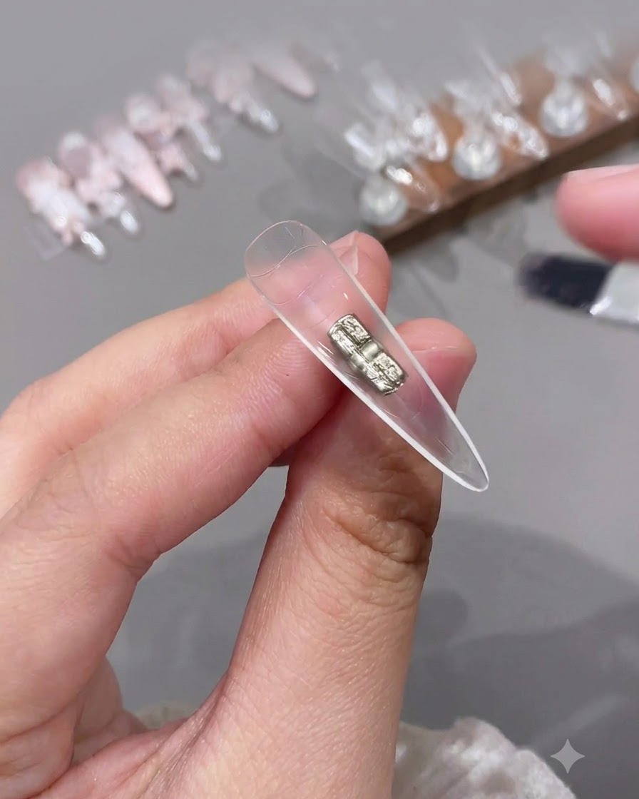Un piccolo pennello applica un top coat trasparente allinterno della sezione cava di una tip per unghie trasparente.