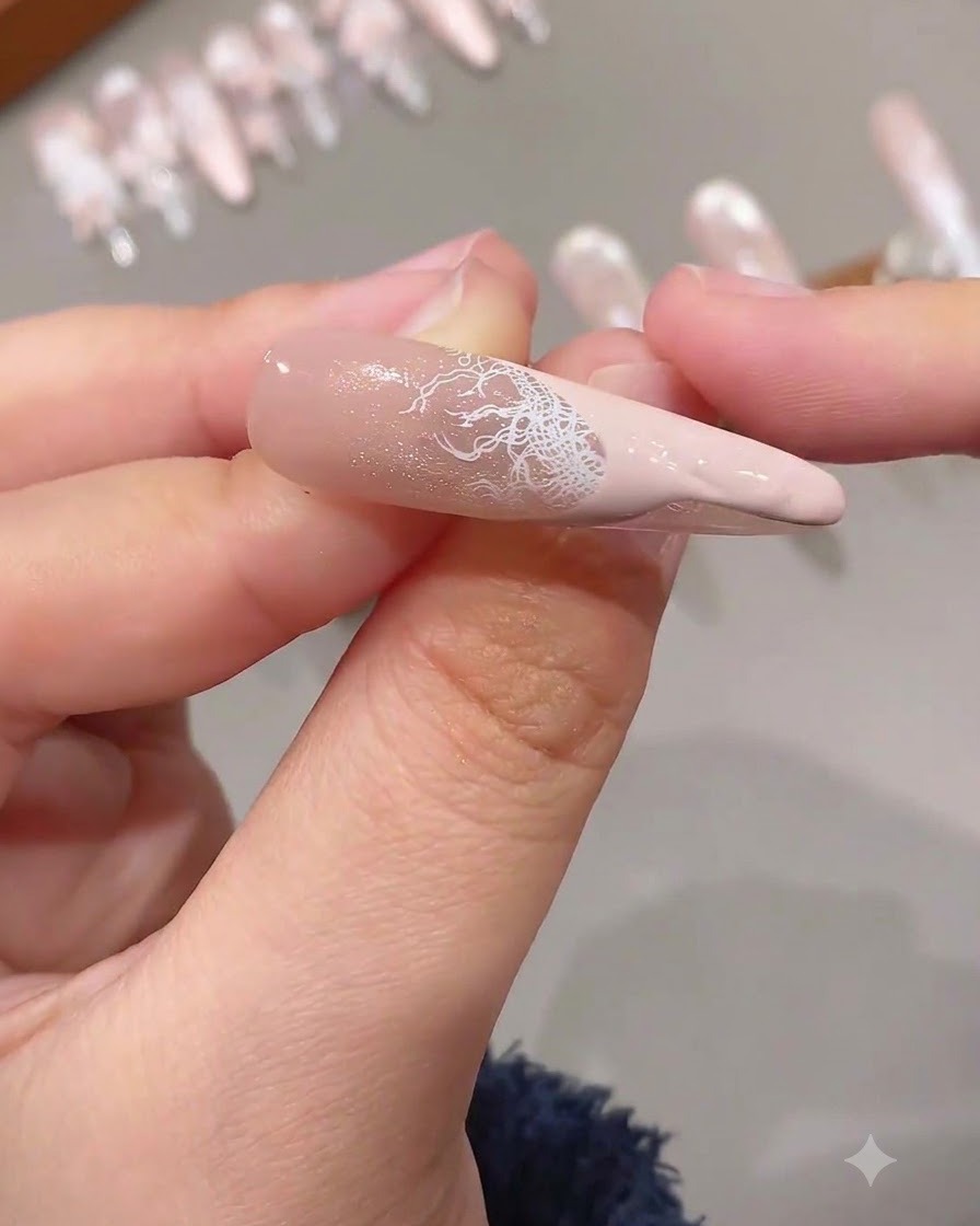 Una french tip completata che presenta unintricata sovrapposizione di pizzo bianco combinata con una punta rosa a tinta unita su ununghia allungata.