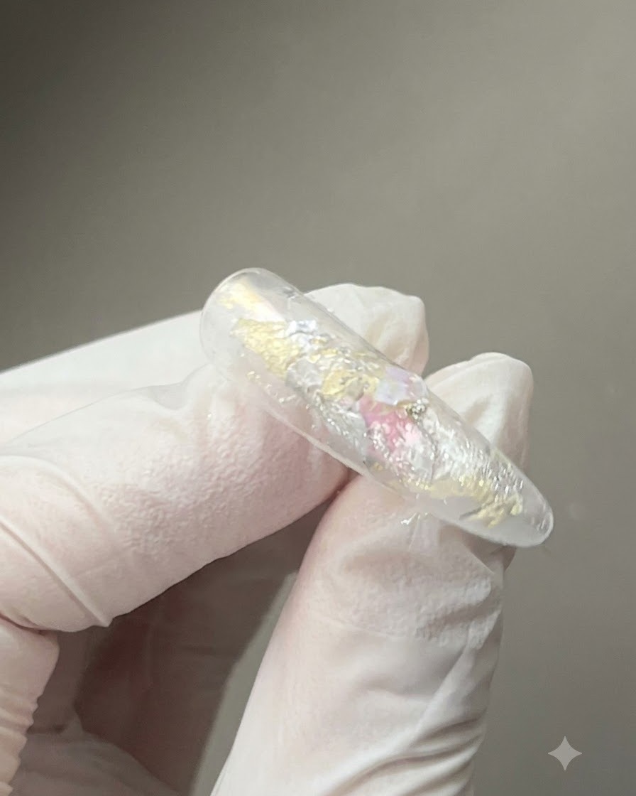 Uno strumento magnetico tenuto vicino a ununghia rivestita di gel lucido per modellare le particelle magnetiche riflettenti cat-eye.