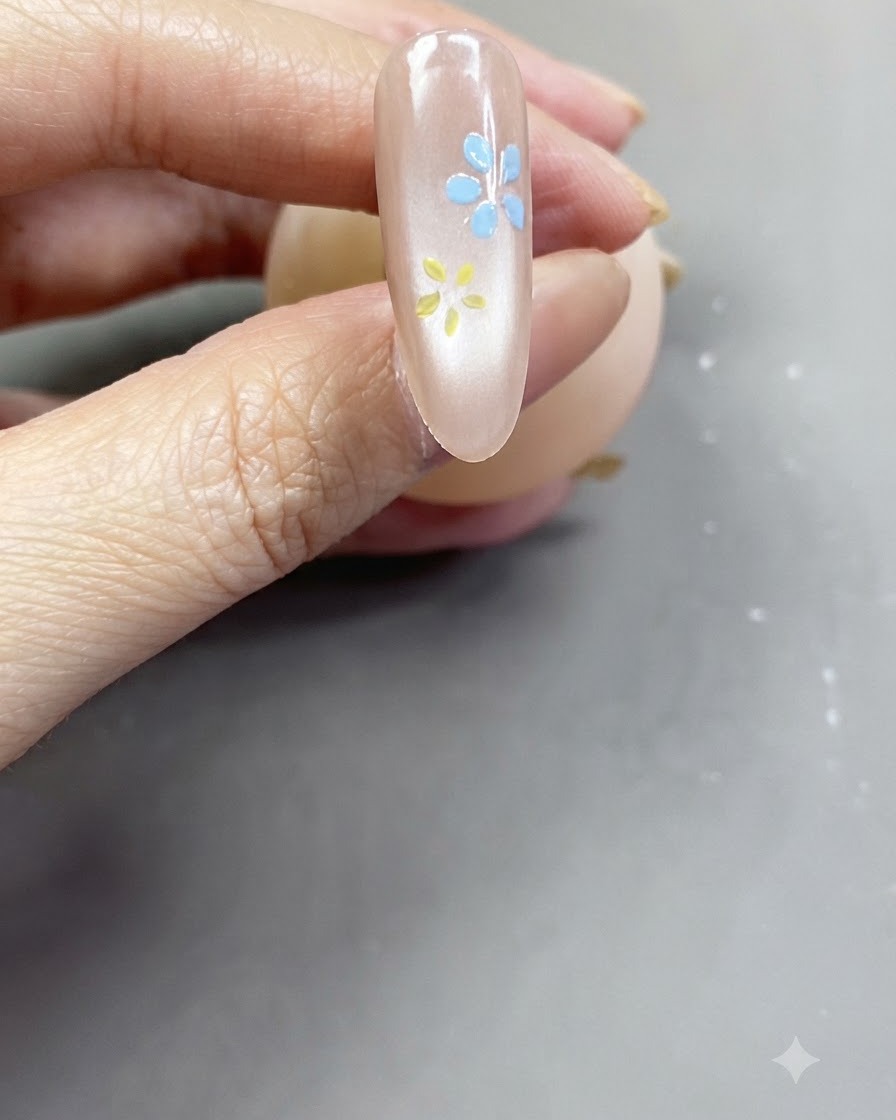 Primo piano di un fiore rosa tenue completato dipinto su ununghia rosa nude lucida.