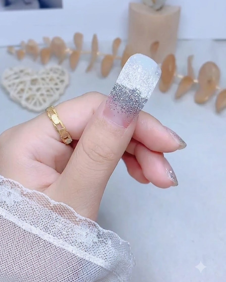 Ununghia del pollice con un adesivo glitter argento premuto saldamente lungo il centro.