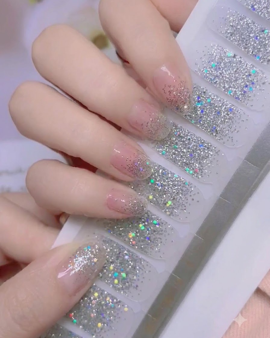 Un pollice che preme saldamente sullarea delle cuticole di un nail wrap con glitter argento.
