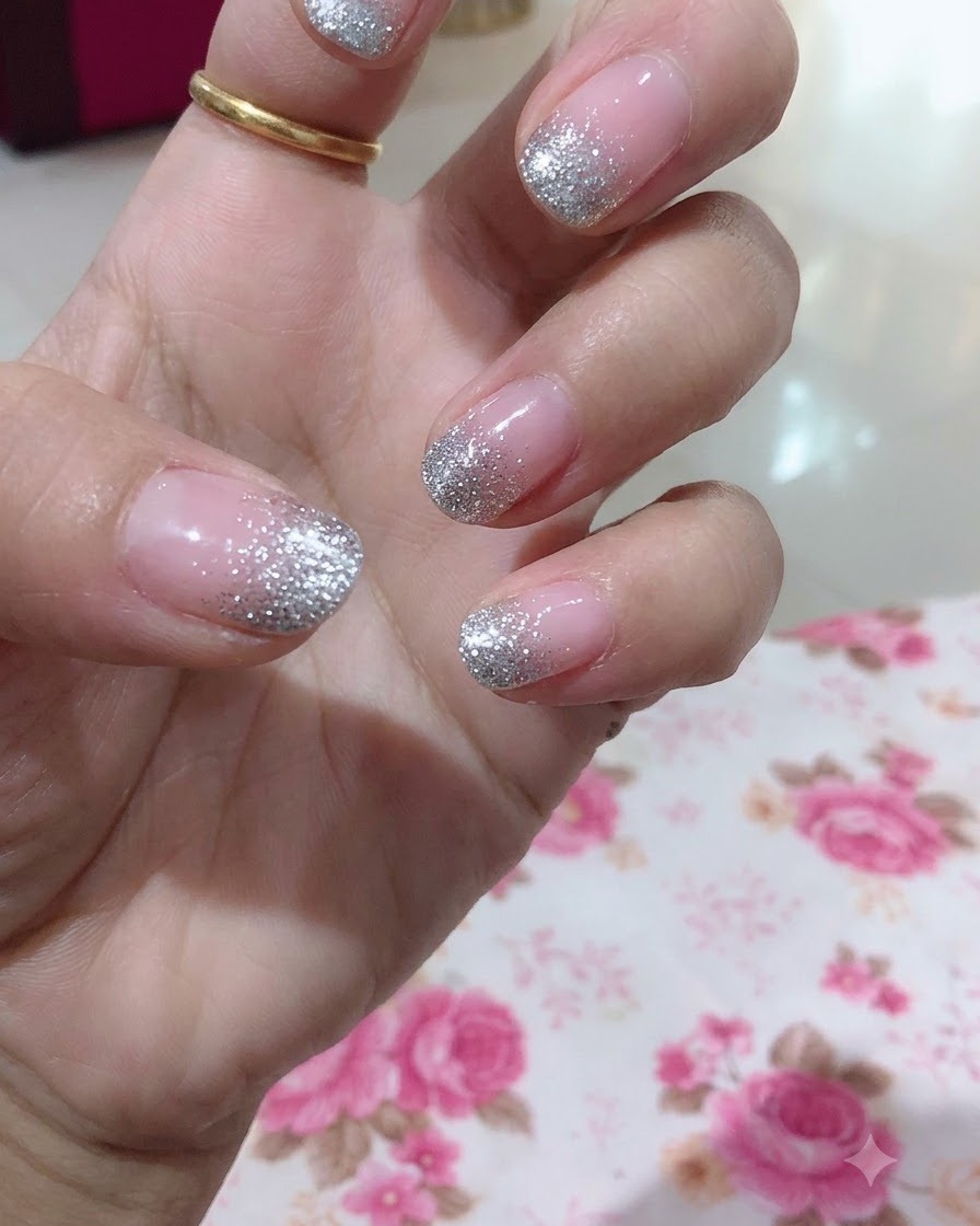 Vista ravvicinata di una mano che evidenzia il dito medio con un design dettagliato di sfumatura glitter argento.