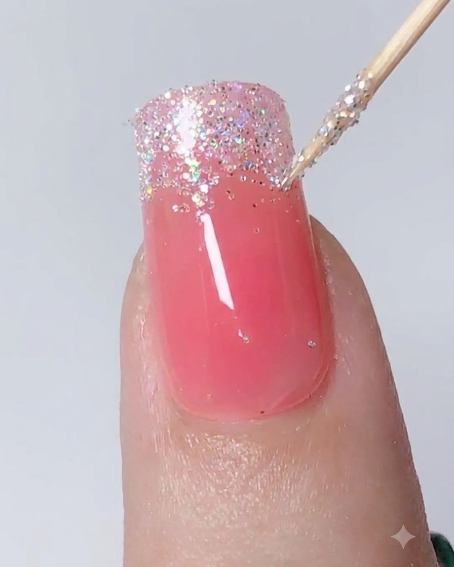 Uno strumento di precisione che tampona e tira i glitter argento verso il basso per creare un gradiente ombré su ununghia.