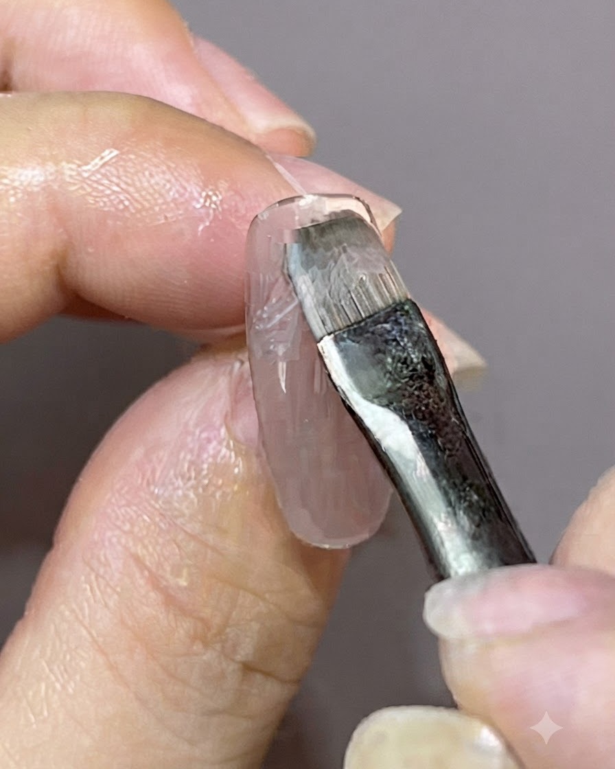 Un pennello di dettaglio che applica un nuovo strato di smalto gel sopra un design per unghie magnetico preesistente.