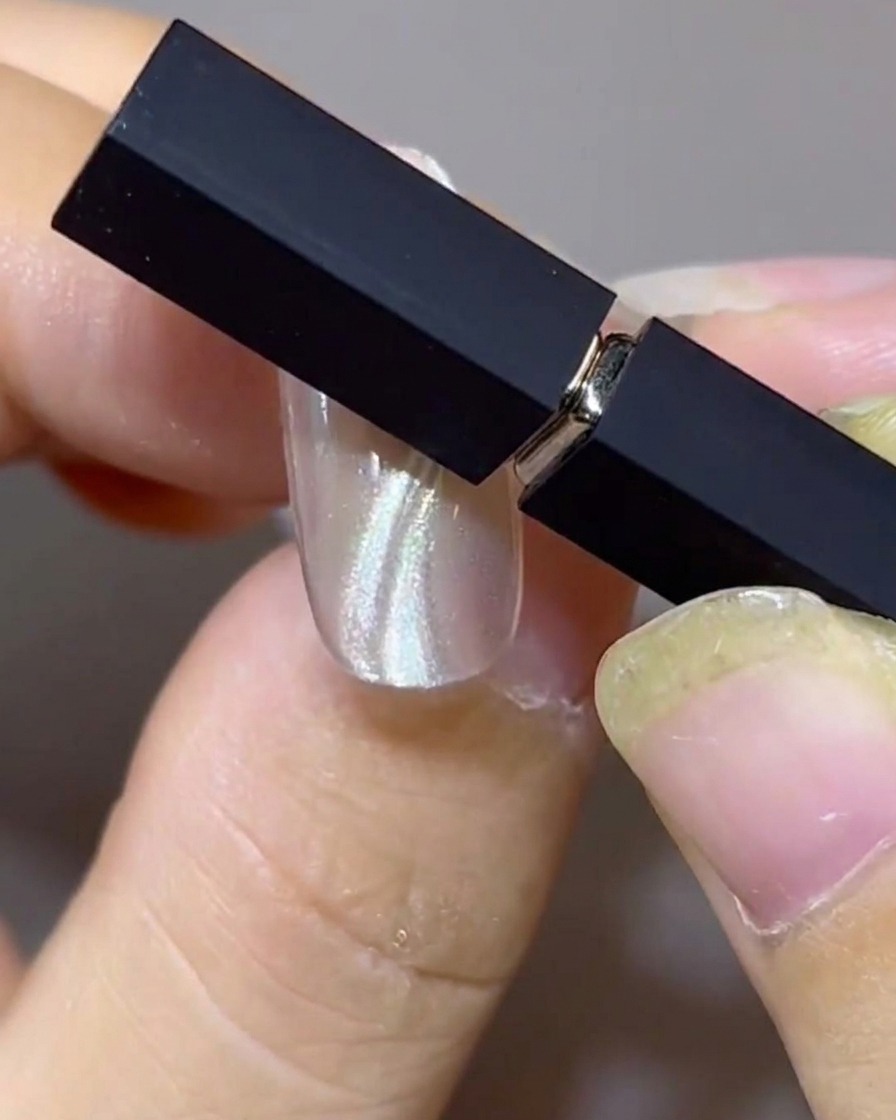 Due magneti posizionati ad angolo sopra ununghia per modellare doppie bande cat-eye fluttuanti parallele.