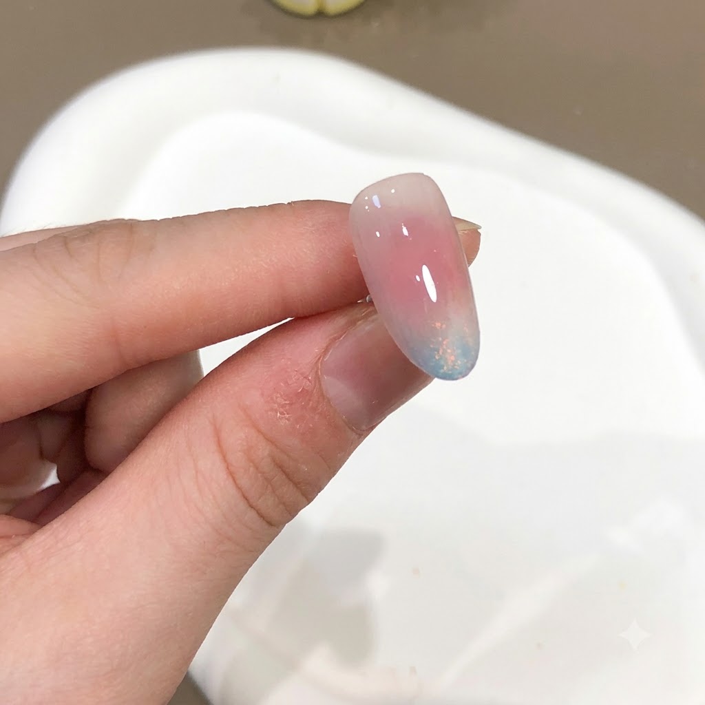 Un primo piano di ununghia che mostra un effetto polvere aurora rosa e blu con una finitura super lucida.