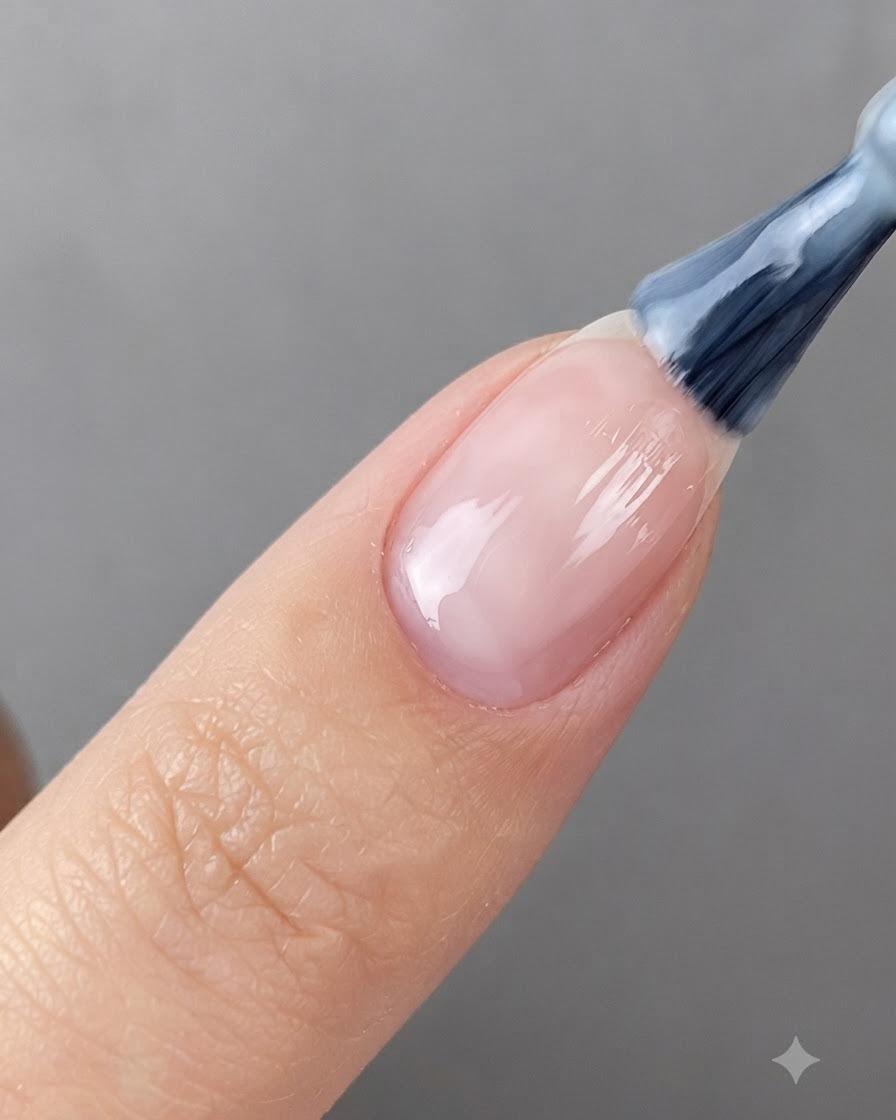 Un pennello per unghie applica il gel bianco traslucido su ununghia preparata.
