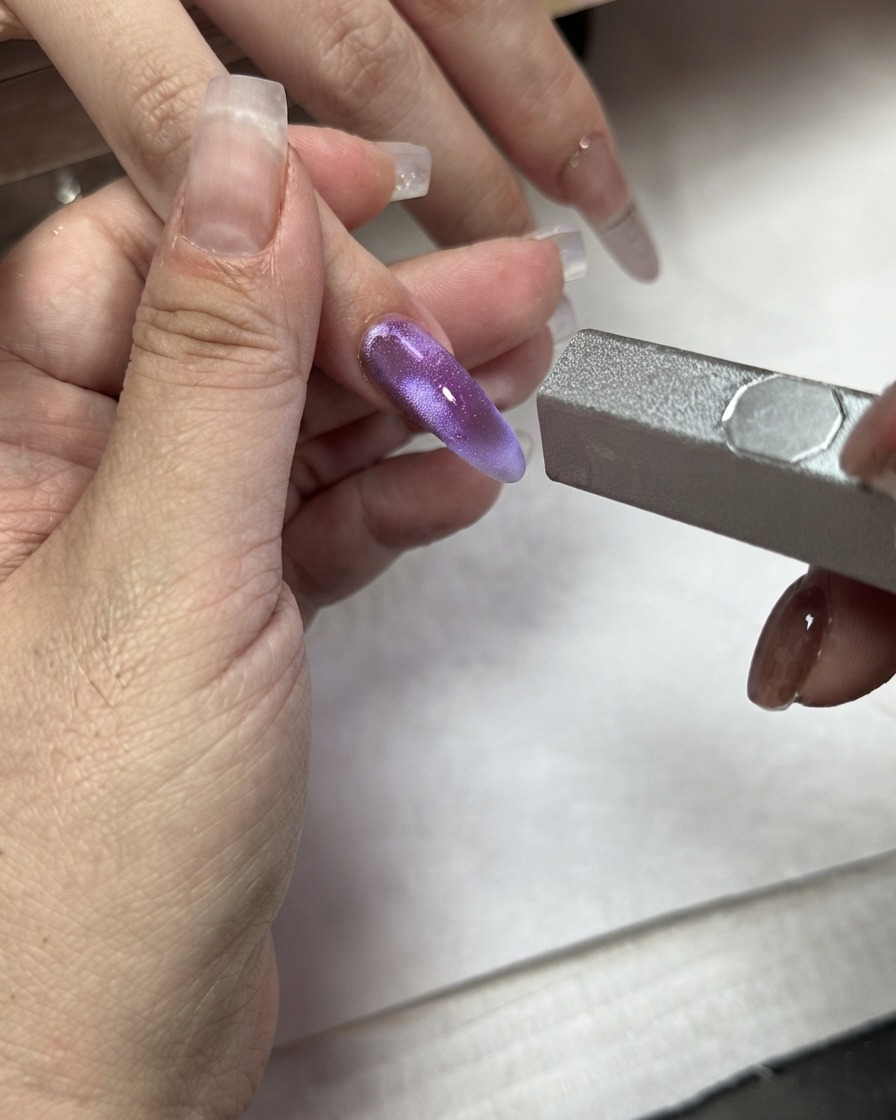 Un magnete utilizzato su un blocco di colore cat eye viola applicato su un dito indice.