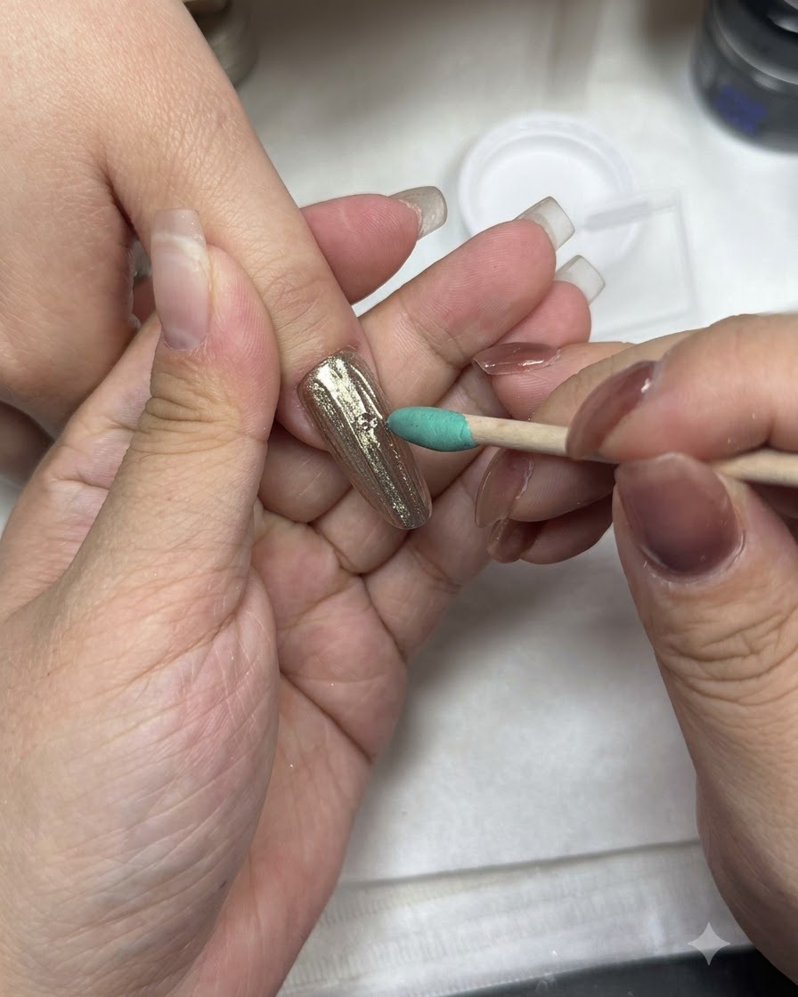 Un pennello da manicure applica il top coat su una superficie ungueale con finitura cromata.