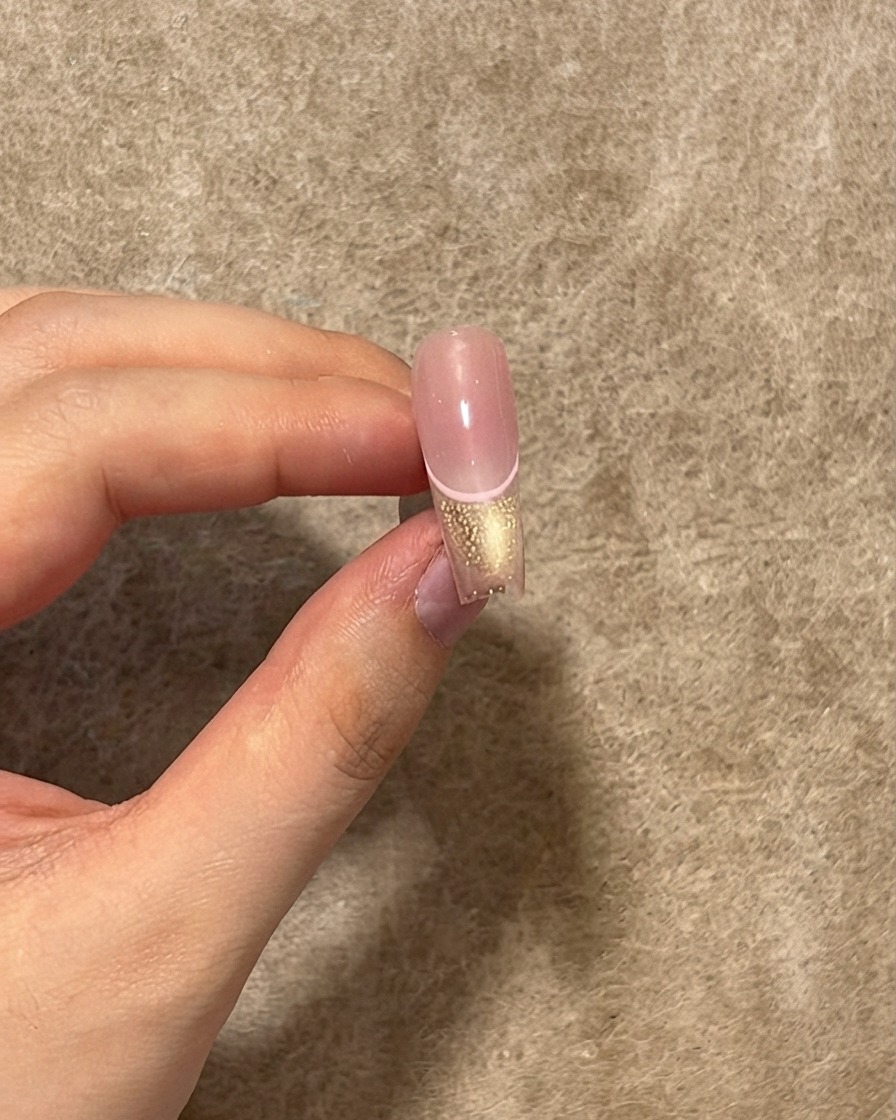 Ununghia finita che mostra uno strato di top coat lucido applicato sopra la linea rosa, la punta cat eye e il centro blush.