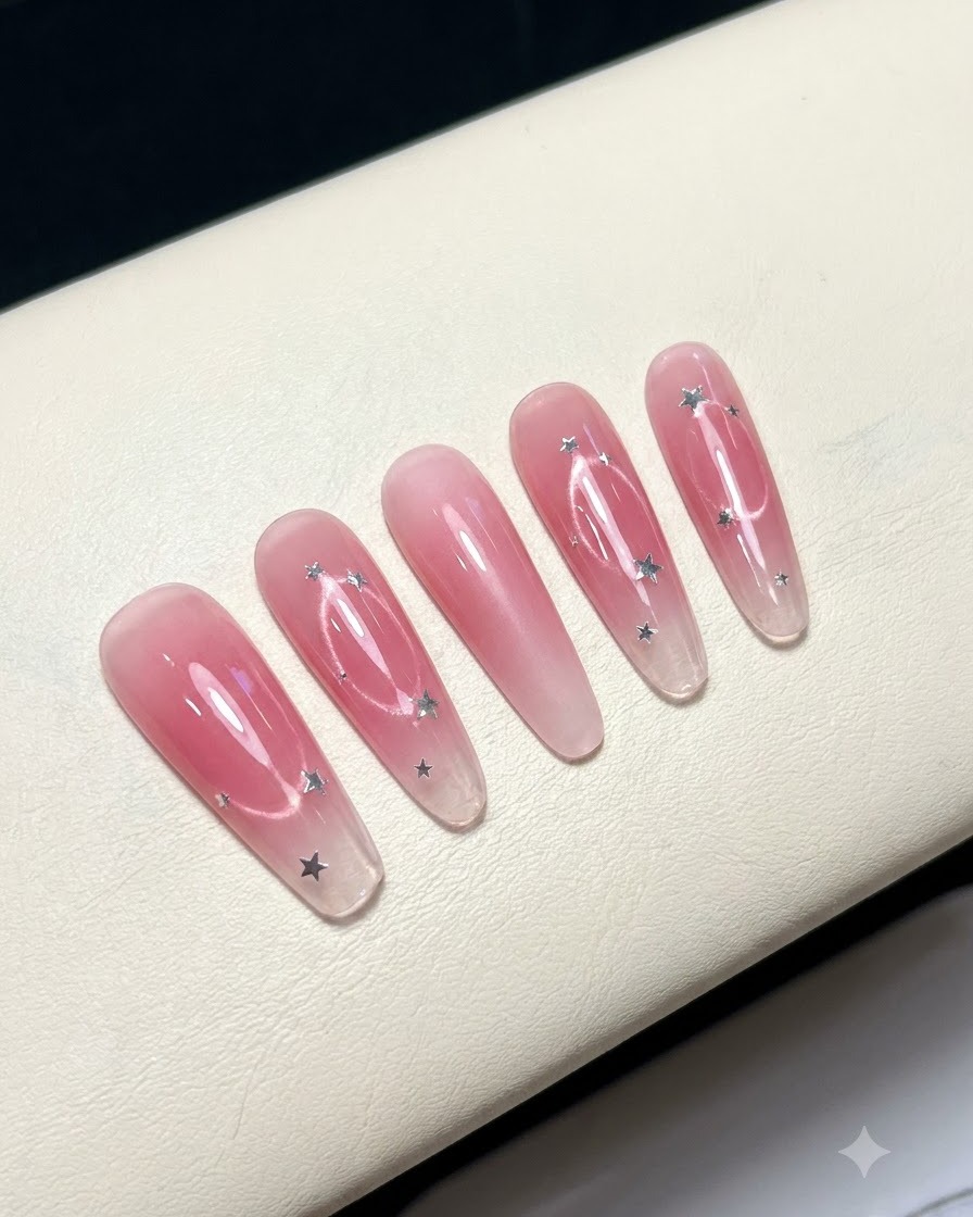 Cinque unghie finte disposte su una superficie bianca che mostrano un design con centro pink blush.